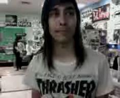 a man with long hair wearing a white shirt and black hat standing in front of a store