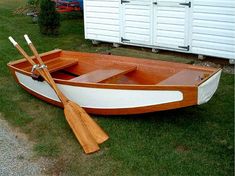 a small wooden boat with oars on the grass