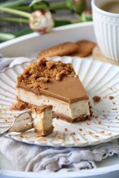 a piece of cheesecake on a plate with a cup of coffee in the background