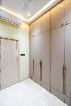 an empty room with beige cupboards and white flooring, including a ceiling fan