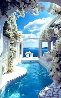 an indoor swimming pool with white flowers on the side and blue sky in the background