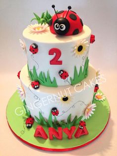 a two tiered cake decorated with ladybugs and daisies