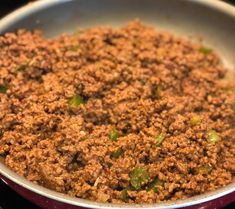 ground beef and green peppers in a pan on top of the stove burner, ready to be cooked