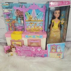 the princess doll is in its box and it's next to her toy kitchen