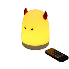 a yellow light with horns on it next to a remote control and a white background