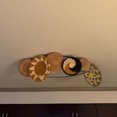 several baskets are hanging on the wall above a shelf with two plates and one basket