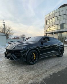 a black sports car is parked in front of a large building on a snowy day