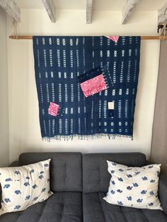 a couch with two pillows on top of it in front of a wall hanging tapestry