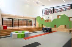 an empty room with tables and chairs on the floor in front of green, yellow, and red walls