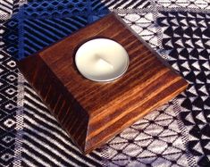 a small wooden candle holder with a white candle inside on a black and white patterned cloth