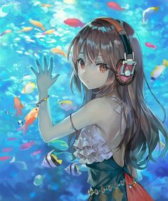 a girl with headphones standing in front of an ocean full of fish and holding her hand up