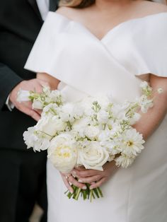 a bride and groom holding white flowers in their hands