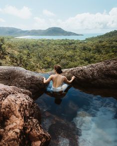 a woman sitting on top of a log in the middle of a body of water