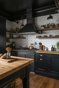 a kitchen with wooden floors and black cabinets, white subway backsplash and open shelving