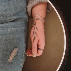 a woman's hand with a tattoo on her left wrist and the other arm