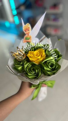 a person holding a bouquet of flowers with tinkerbells on it and a fairy tale brooch