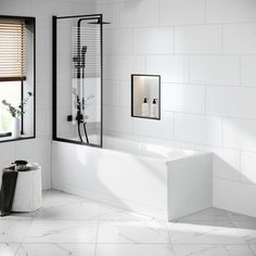 a bathroom with white tile and black trimmings on the walls, along with a large bathtub