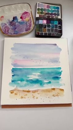 some watercolors are sitting on a table next to an empty tray and paintbrush