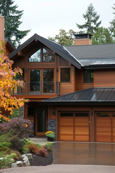 a large house with lots of windows and wooden garage doors