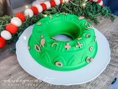 a green frosted cake sitting on top of a white plate next to a garland