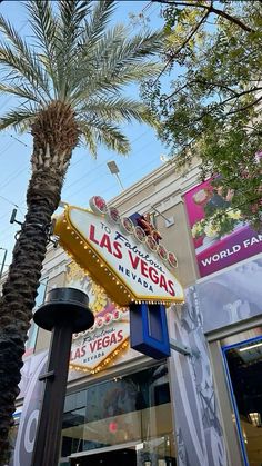 the las vegas sign is next to a palm tree in front of a storefront