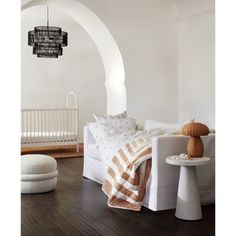 a bedroom with white walls and wood flooring is pictured in this image, there are two round lamps hanging from the ceiling