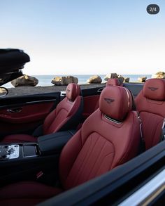 the interior of a car with red leather and black trim, along with an ocean view