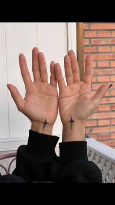 a woman with her hands in the air and two cross tattoos on her left wrist