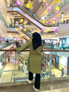 a woman in a hijab is looking down at the stairs inside a shopping mall