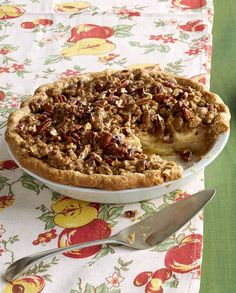 a pie sitting on top of a table next to a knife and fork with a slice missing from it