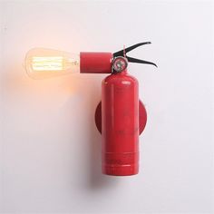 a red fire extinguisher is attached to the wall with a light bulb