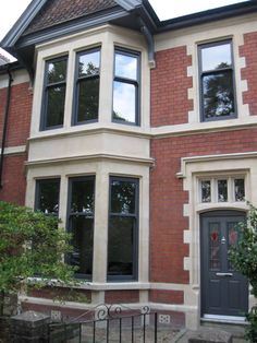 a large brick house with two story windows and a black gate in front of it