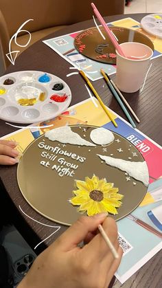 a person painting on a plate with sunflowers