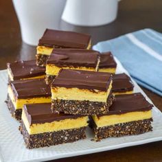 several pieces of chocolate and yellow cake on a white plate next to a glass of milk