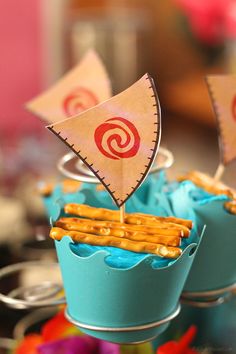 two cupcakes decorated like boats with flags on top and blue frosting in the middle