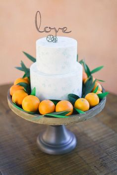 a wedding cake with oranges and greenery on top