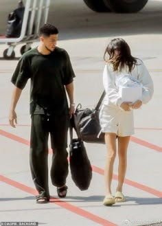 the man and woman are walking towards an airplane