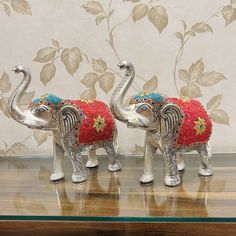 two silver elephants with red and blue blankets on their backs, standing next to each other