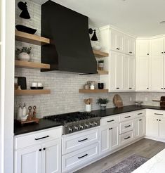 a kitchen with white cabinets, black counter tops and open shelving above the stove