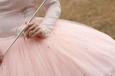 a woman in a pink dress is holding a stick