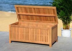 a large wooden box sitting on top of a sidewalk next to a potted plant