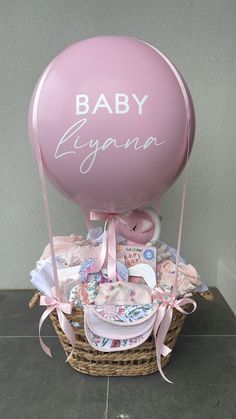 a pink balloon sitting on top of a basket filled with baby items