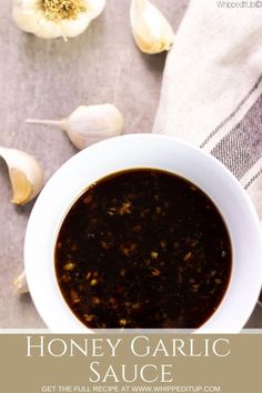 honey garlic sauce in a white bowl on top of a towel next to garlic bulbs