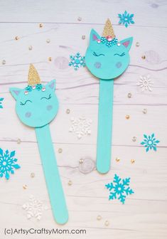 two wooden spoons decorated with blue and gold glitter, one has a cat's head on it