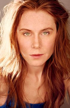 a woman with freckled hair and green eyes looks at the camera while posing for a portrait