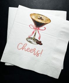 two napkins with an image of a drink in it and the words cheers on them