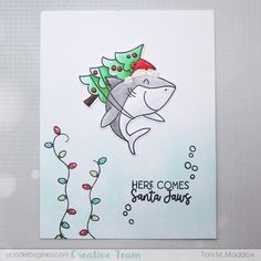 a shark with a christmas tree on its head is in front of a card that says, here comes santa claus