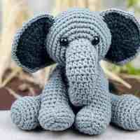 a crocheted elephant sitting on top of a cement slab