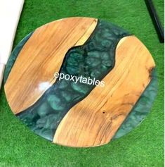 a wooden plate with green and brown designs on it, sitting on the grass in front of a white chair