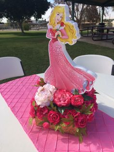 there is a pink table with flowers and a princess figurine on top of it